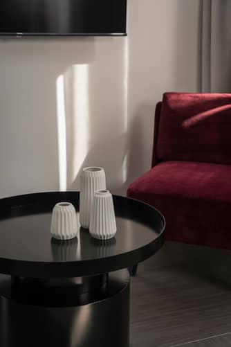 Dettaglio dell’ambiente interno di Casa Guttmann a Roma con vasi di arredo e divano in velluto rosso